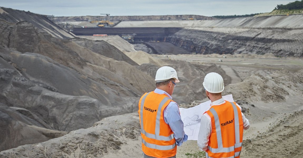 Two TAKRAF employees standing in the open pit looking at a drawing