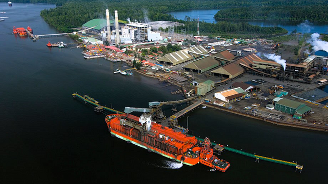 A red ship lies in front of the harbor in Indonesia.