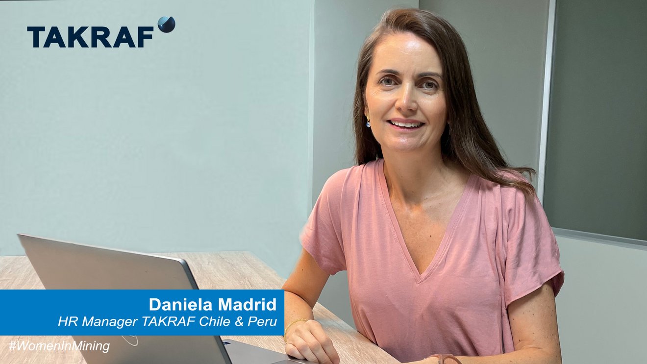 Daniela Madrid, smiling, sitting at a desk with a laptop in front of her
