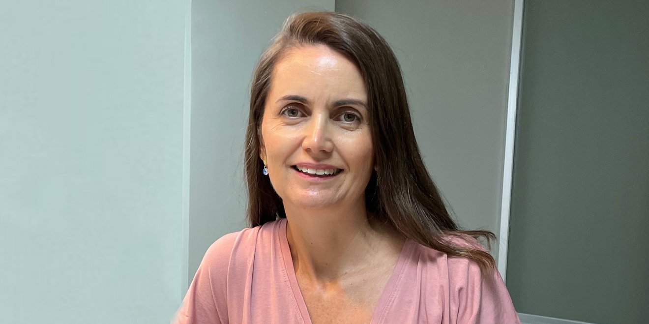 Daniela Madrid, smiling, sitting at a desk with a laptop in front of her