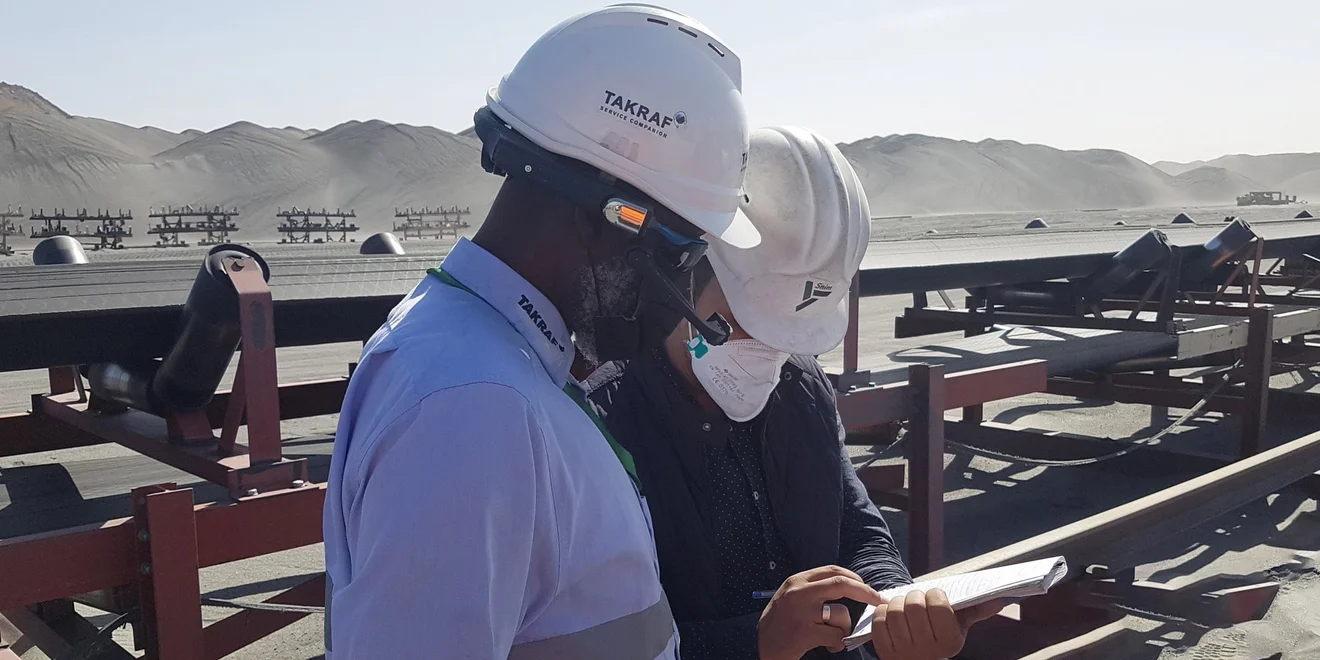 Two men talking about project details infront of a conveyor.