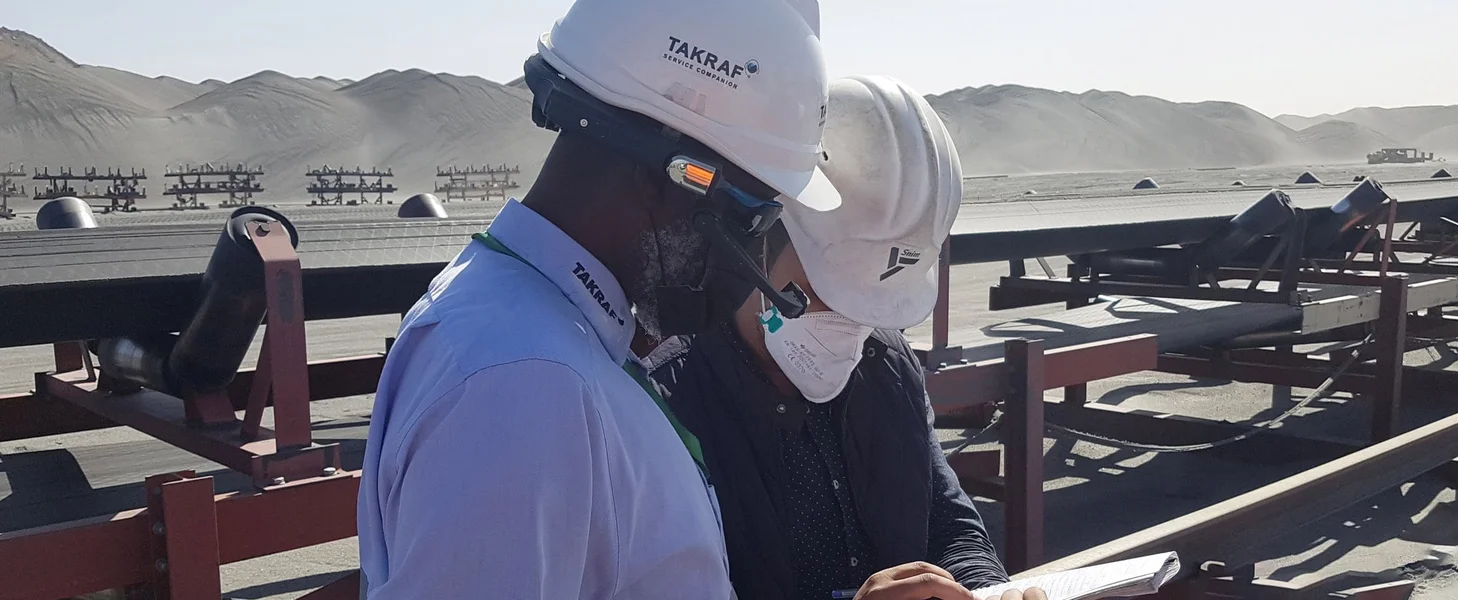 Two men talking about project details infront of a conveyor.