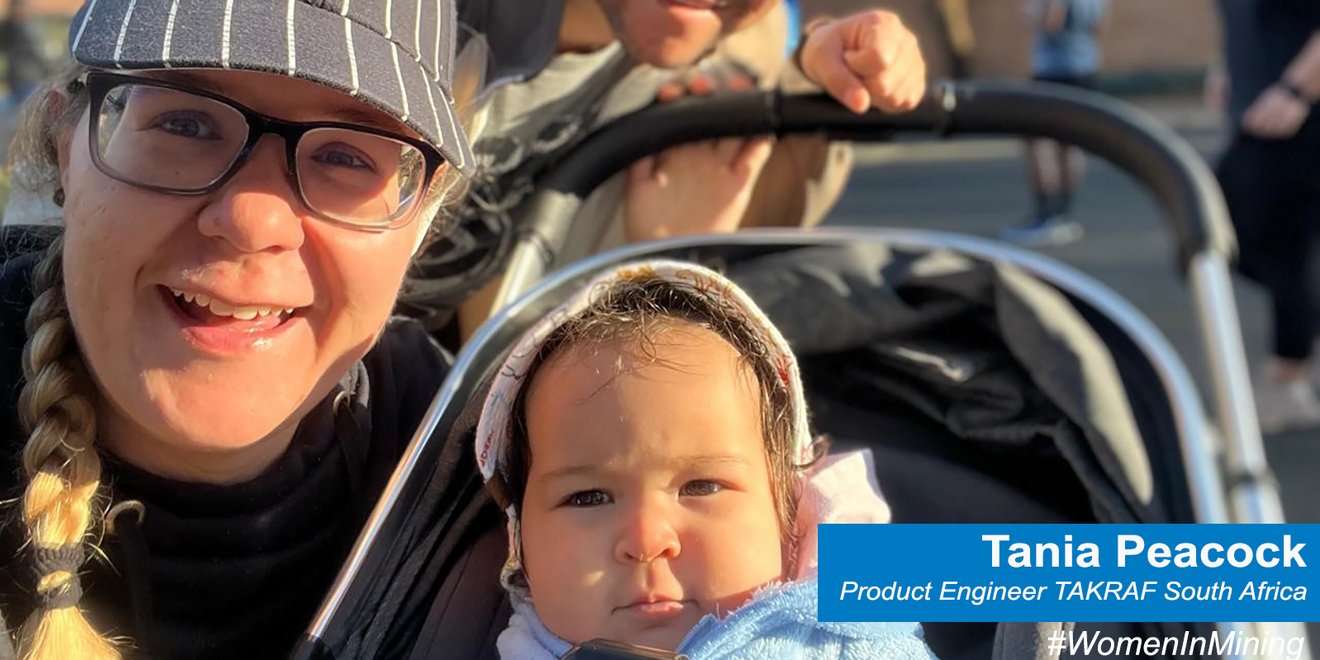 Tania Peacock smiling next to her daughter in a stroller and her husband in the back 