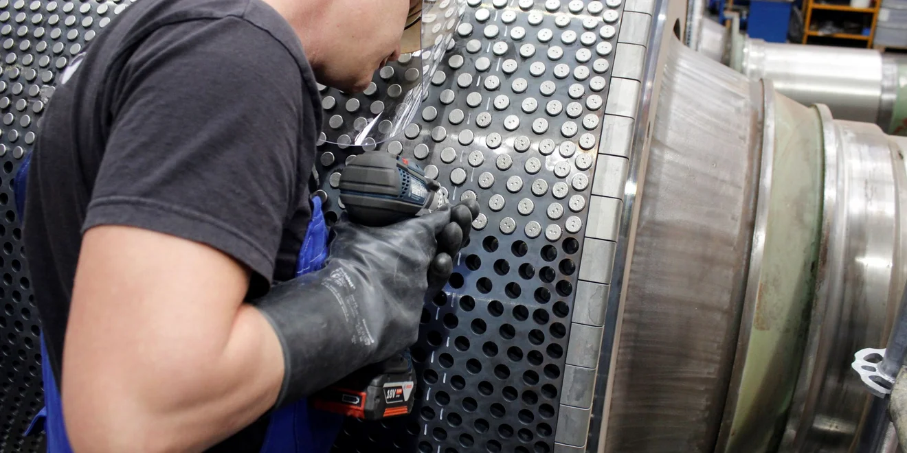Refurbishment of a HPGR in Lauchhammer, Germany. A production worker is refurbishing a High Pressure Grinding Roll.