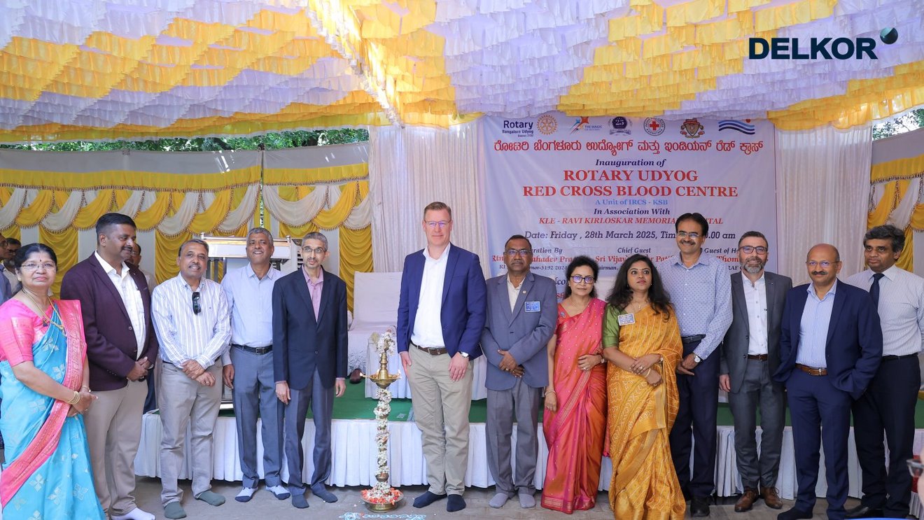 A group of people, including TAKRAF and DELKOR representatives, Rotary Udyog and Red Cross members, standing in front of a banner reading ‘Rotary Udyog Red Cross Blood Centre