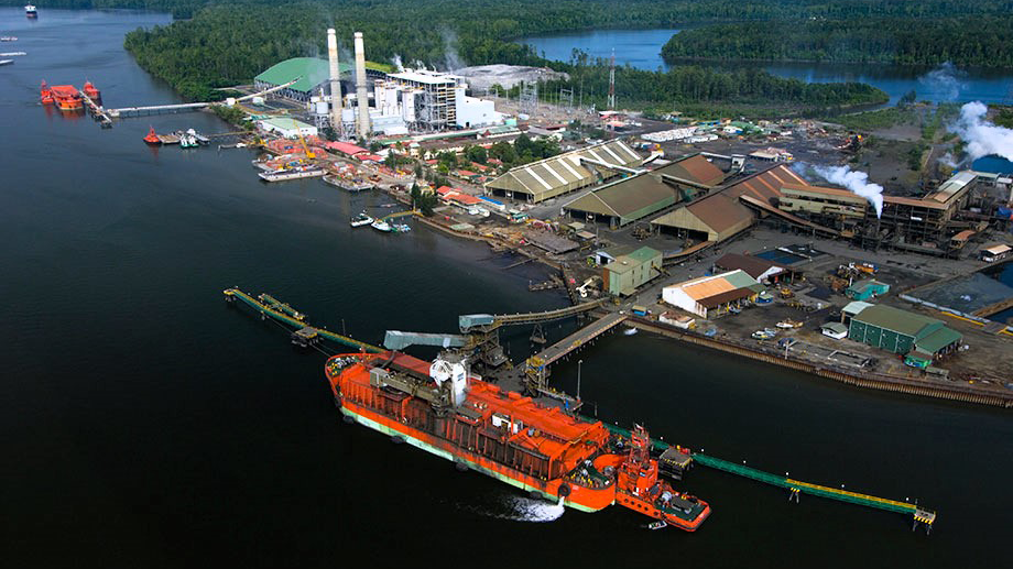 A red ship lies in front of the harbor in Indonesia.
