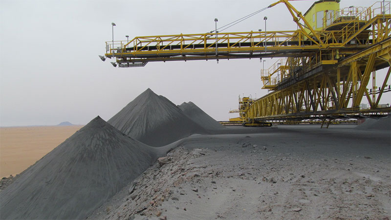 yellow conveyor bridge stacking filtered tailings into a pile, illustrating TAKRAF’s dry-stack tailings management system