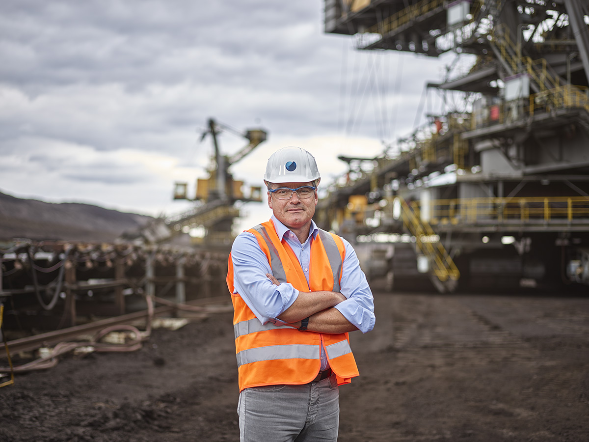 Man with helmet and safety vest in front of a construction site